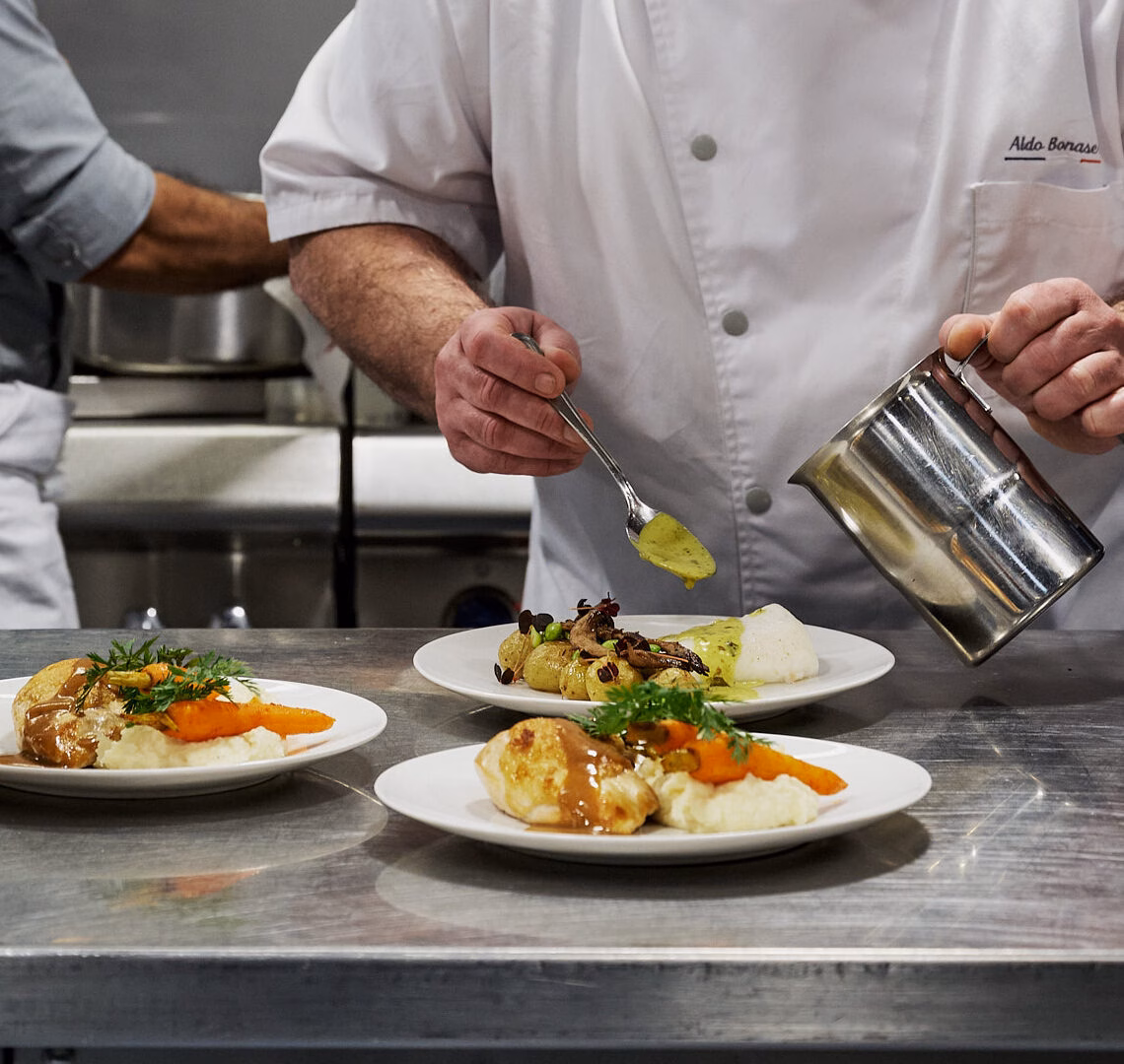 Chef préparant des plats gastronomiques pour un dîner croisière sur la Seine à Paris, mettant en valeur la cuisine française | Le Capitaine Fracasse